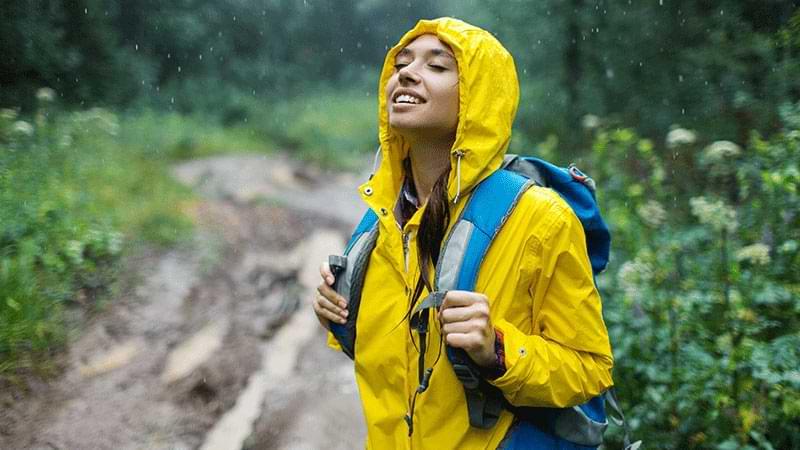 穿着雨衣的年轻女子在雨中享受大自然